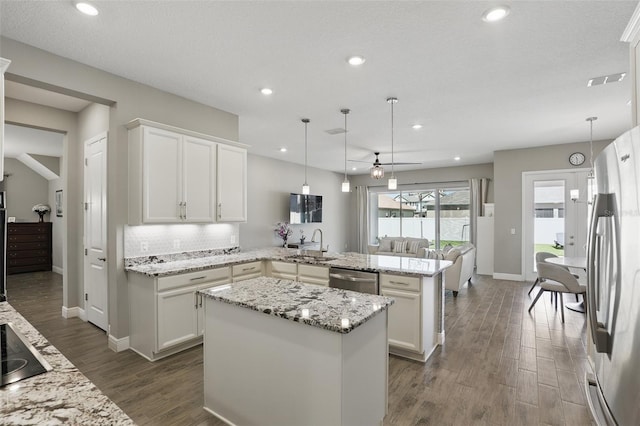 kitchen with dark wood-style floors, a peninsula, a sink, appliances with stainless steel finishes, and white cabinetry