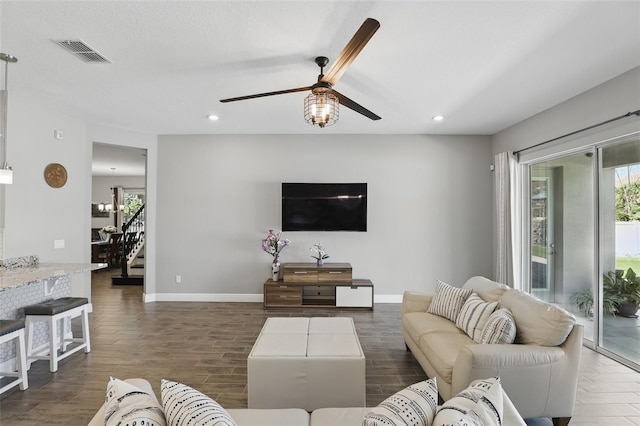 living room featuring a wealth of natural light, visible vents, stairs, and dark wood-style flooring