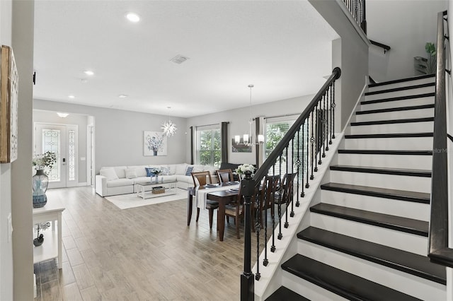 stairway with visible vents, recessed lighting, an inviting chandelier, and wood finished floors