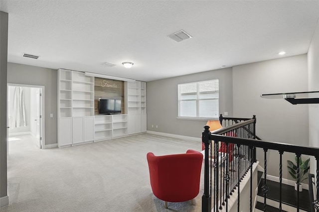 carpeted living area with visible vents, baseboards, and a textured ceiling