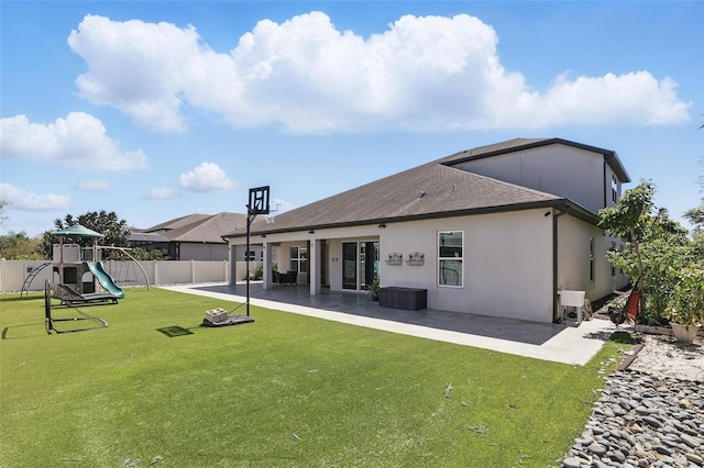 back of property with stucco siding, a playground, fence, a yard, and a patio area