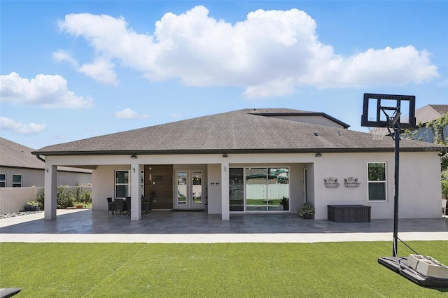 back of property with a yard, a shingled roof, stucco siding, french doors, and a patio area