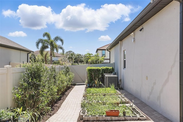 view of yard with a garden, fence, and central AC