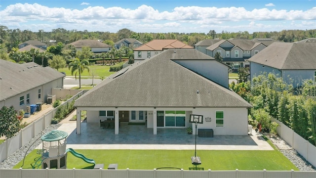 rear view of property featuring a patio, a playground, a fenced backyard, and a lawn