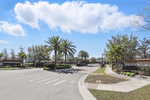 view of street with sidewalks, curbs, a gated entry, and a gate