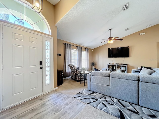 entryway with lofted ceiling, light wood-style flooring, visible vents, and a textured ceiling