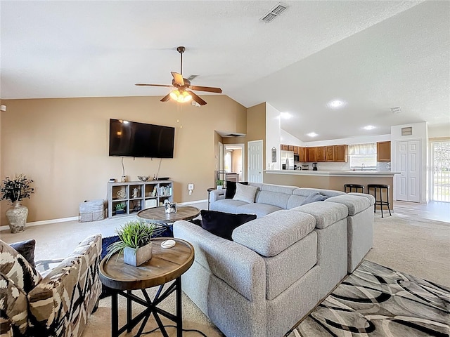 living area with light carpet, baseboards, visible vents, and lofted ceiling