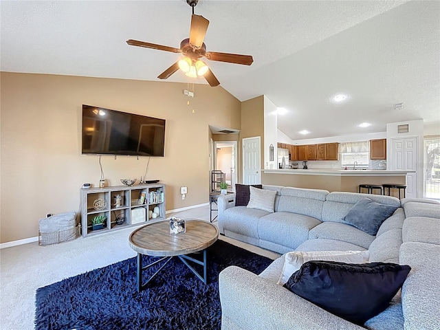 carpeted living area featuring ceiling fan, a sink, visible vents, baseboards, and vaulted ceiling