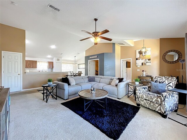 carpeted living area with baseboards, visible vents, ceiling fan, vaulted ceiling, and a textured ceiling