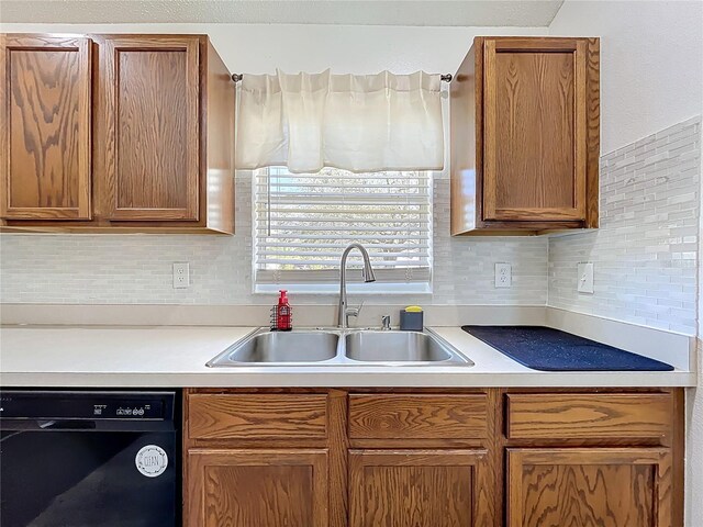 kitchen with dishwasher, light countertops, tasteful backsplash, and a sink