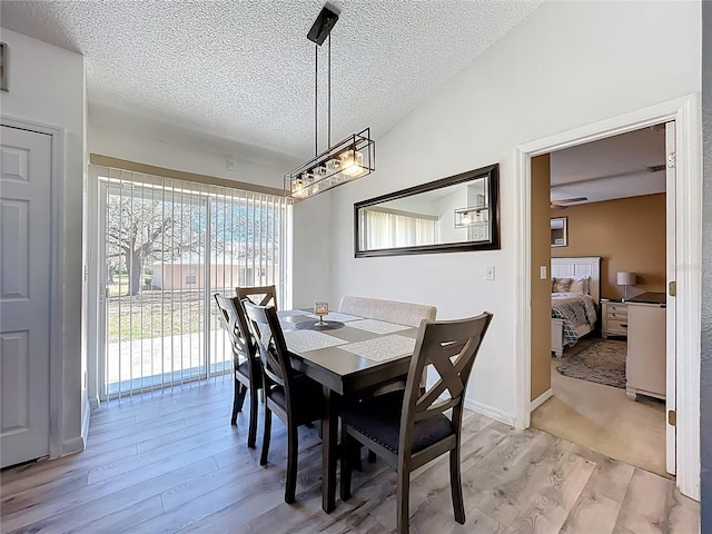 dining room with lofted ceiling, a textured ceiling, and light wood-style flooring