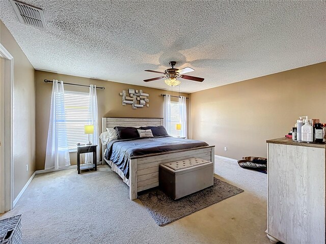 carpeted bedroom with ceiling fan, a textured ceiling, visible vents, and baseboards