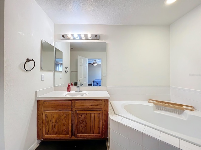 full bath featuring ensuite bathroom, a textured ceiling, a garden tub, vanity, and a ceiling fan