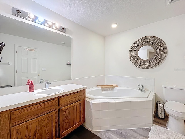 bathroom with toilet, wood finished floors, a textured ceiling, vanity, and a bath