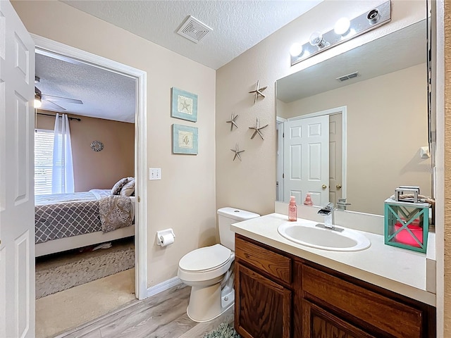 ensuite bathroom with a textured ceiling, toilet, visible vents, and ensuite bathroom