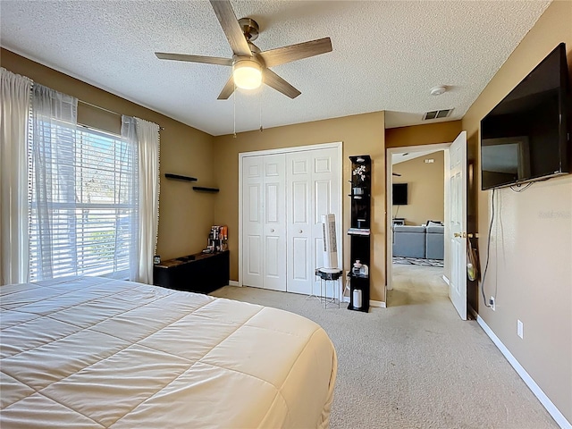 bedroom featuring visible vents, light colored carpet, a textured ceiling, washer and dryer, and a closet