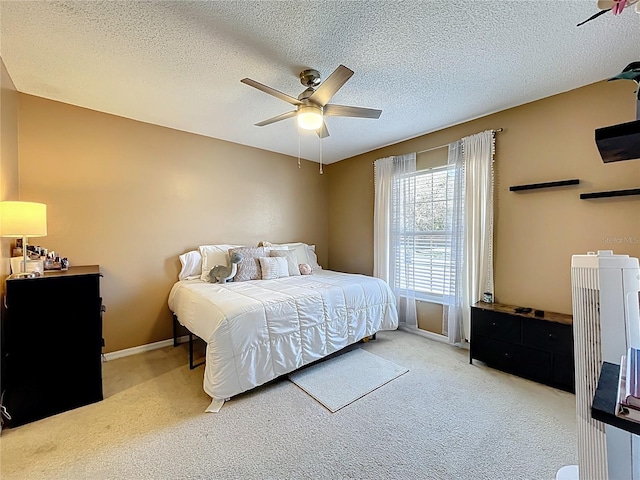 bedroom with a textured ceiling, carpet floors, a ceiling fan, and baseboards