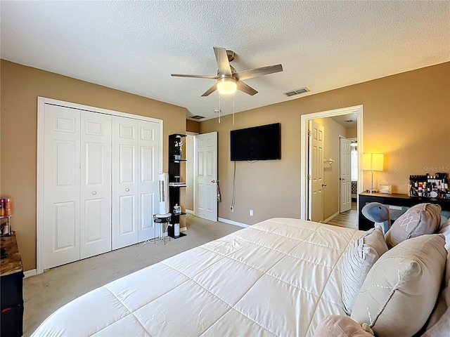 bedroom featuring light carpet, baseboards, visible vents, a textured ceiling, and a closet