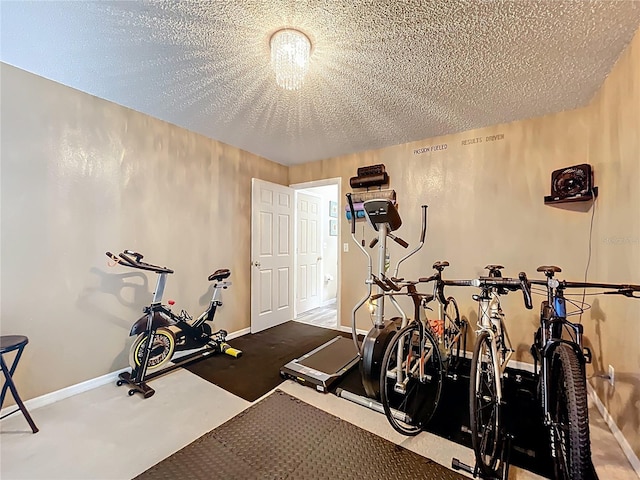 exercise area featuring a textured ceiling and baseboards