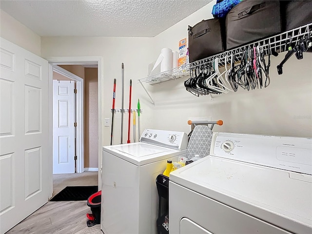 clothes washing area featuring a textured ceiling, laundry area, light wood finished floors, and washing machine and dryer