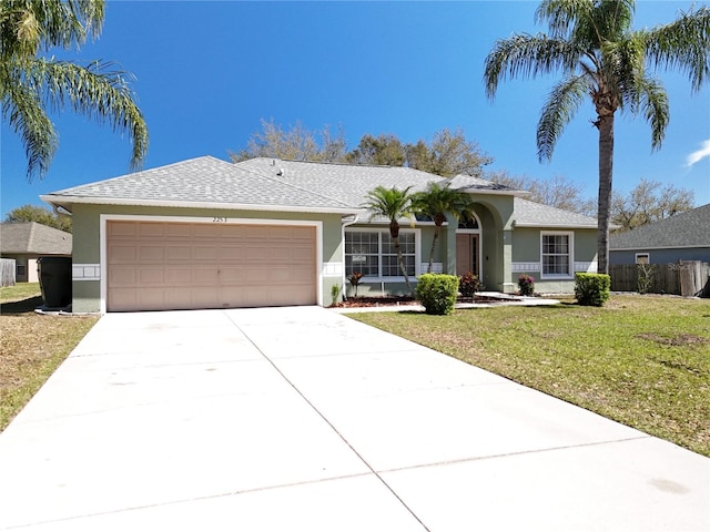 ranch-style home with a garage, a front yard, concrete driveway, and stucco siding