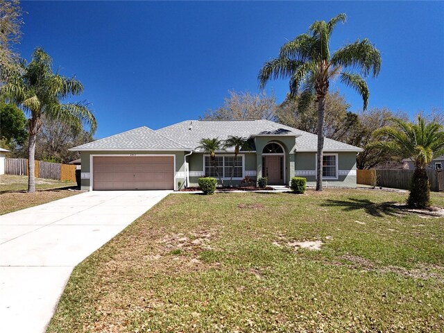 ranch-style house featuring an attached garage, driveway, fence, and a front yard