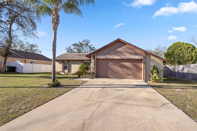 view of front facade with stucco siding, driveway, a front lawn, fence, and a garage