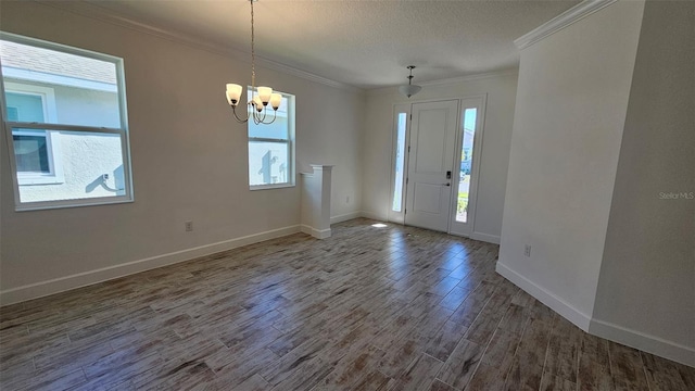 entrance foyer with an inviting chandelier, ornamental molding, a textured ceiling, wood finished floors, and baseboards