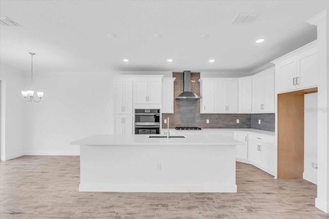 1067 Signet, Apollo Beach, FL 33572 - kitchen featuring wall chimney exhaust hood, stainless steel double oven, an island with sink, a chandelier, and light countertops