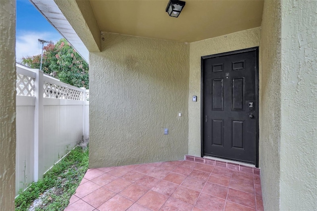 property entrance with fence and stucco siding