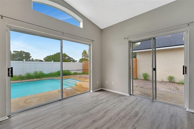 doorway to outside with baseboards, vaulted ceiling, and wood finished floors