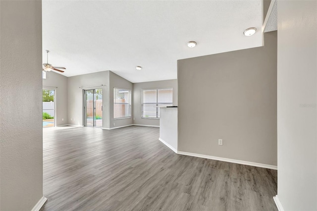 unfurnished living room featuring lofted ceiling, a ceiling fan, baseboards, and wood finished floors