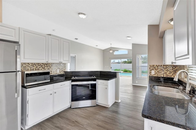 kitchen featuring a peninsula, appliances with stainless steel finishes, a sink, and white cabinetry