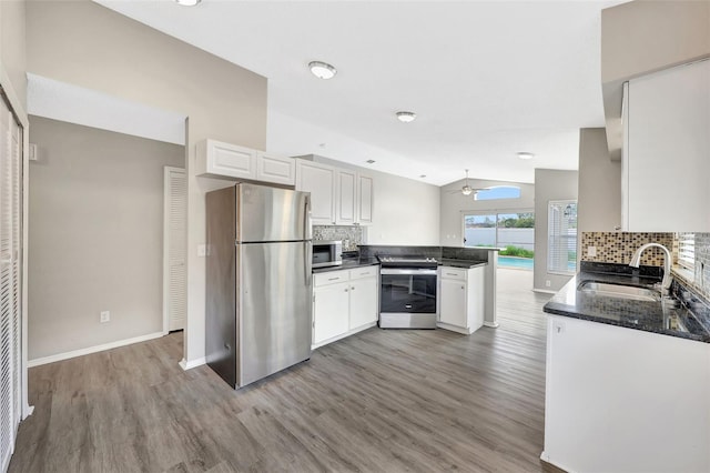 kitchen with appliances with stainless steel finishes, backsplash, a sink, and a peninsula