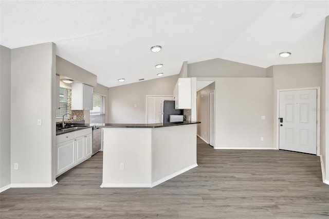 kitchen with freestanding refrigerator, white cabinets, a sink, and dark countertops