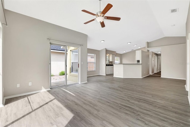 unfurnished living room with lofted ceiling, ceiling fan, wood finished floors, visible vents, and baseboards