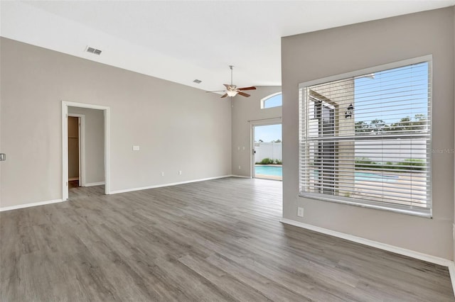 spare room featuring lofted ceiling, visible vents, ceiling fan, wood finished floors, and baseboards