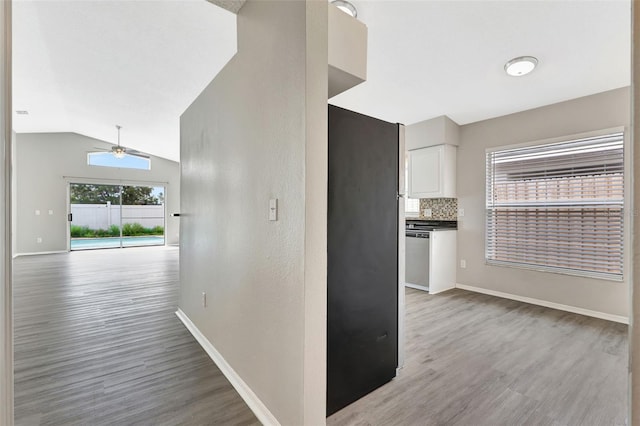 interior space featuring light wood-type flooring, vaulted ceiling, and baseboards