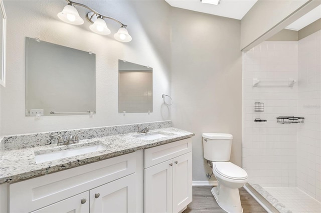 bathroom featuring double vanity, wood finished floors, a sink, and toilet