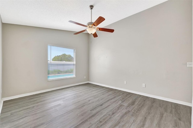 unfurnished room featuring lofted ceiling, ceiling fan, a textured ceiling, wood finished floors, and baseboards