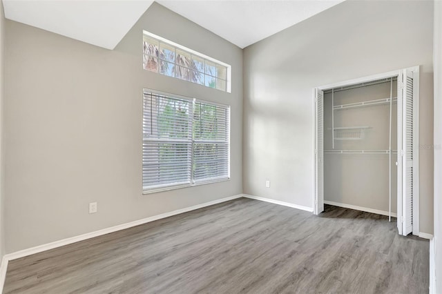 unfurnished bedroom featuring a closet, baseboards, and wood finished floors