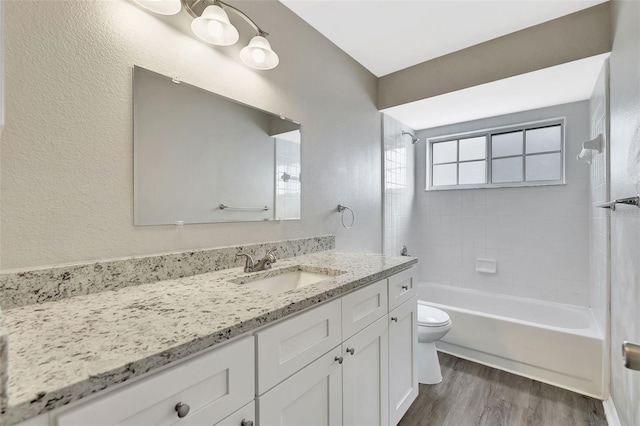 bathroom featuring a textured wall, toilet, vanity, shower / tub combination, and wood finished floors