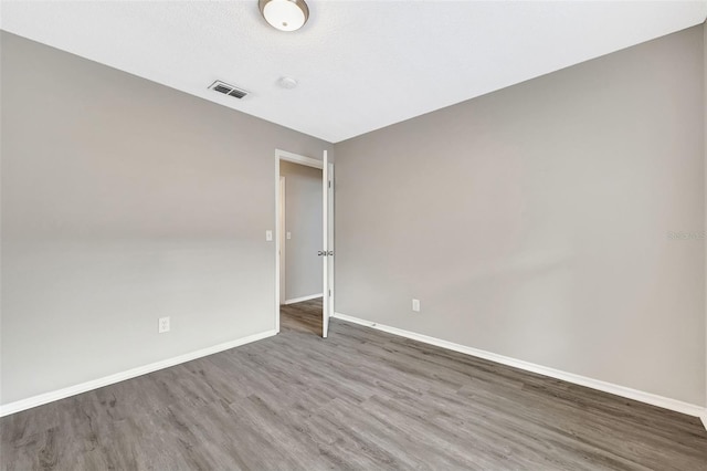 unfurnished room featuring baseboards, a textured ceiling, visible vents, and wood finished floors