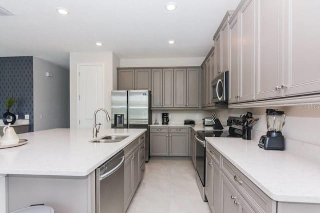 kitchen featuring a center island with sink, stainless steel appliances, recessed lighting, gray cabinetry, and a sink