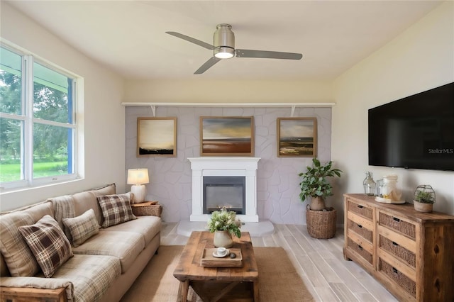 living room with a ceiling fan, wood tiled floor, and a glass covered fireplace