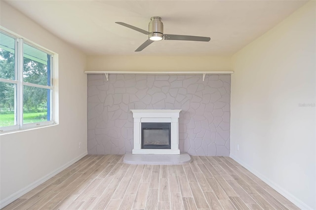 unfurnished living room featuring ceiling fan, wood finish floors, a glass covered fireplace, and baseboards