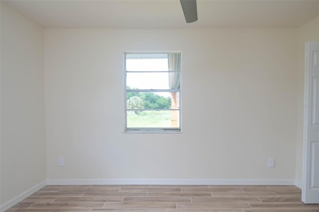 empty room with wood tiled floor, ceiling fan, and baseboards