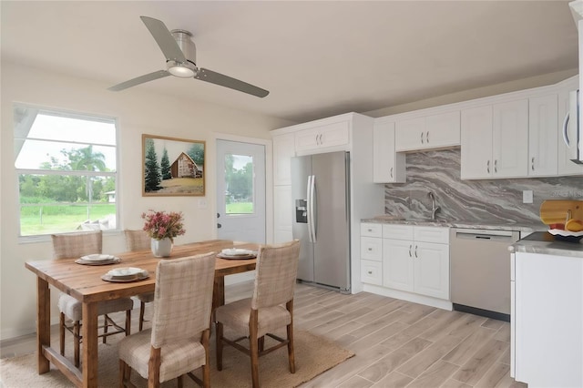 kitchen featuring dishwashing machine, white cabinets, backsplash, light wood finished floors, and stainless steel fridge