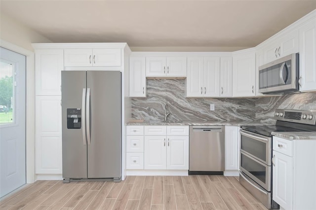 kitchen with white cabinets, tasteful backsplash, wood tiled floor, and stainless steel appliances