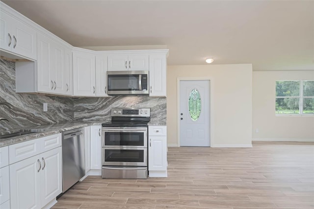 kitchen with stainless steel appliances, tasteful backsplash, light wood-style floors, white cabinetry, and baseboards